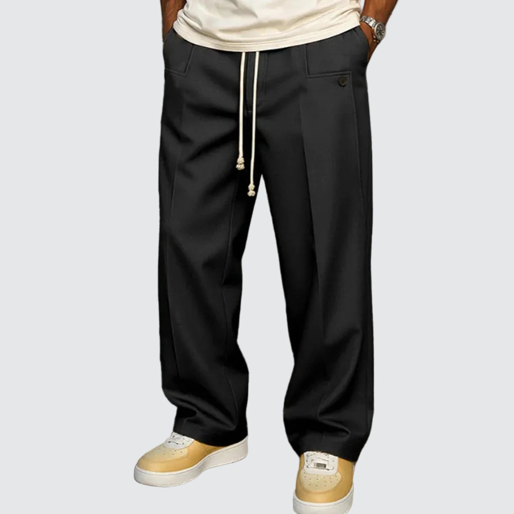 Person wearing black drawstring pants with a plain background